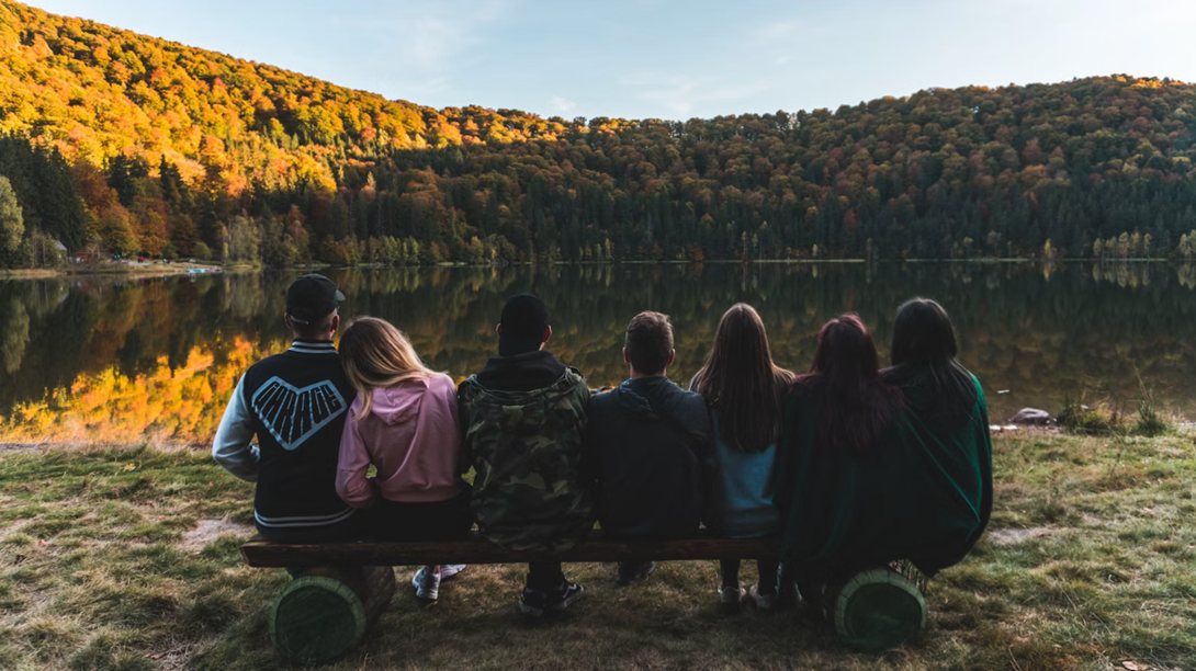 Un grupo de personas frente a un lago, en reflexión
